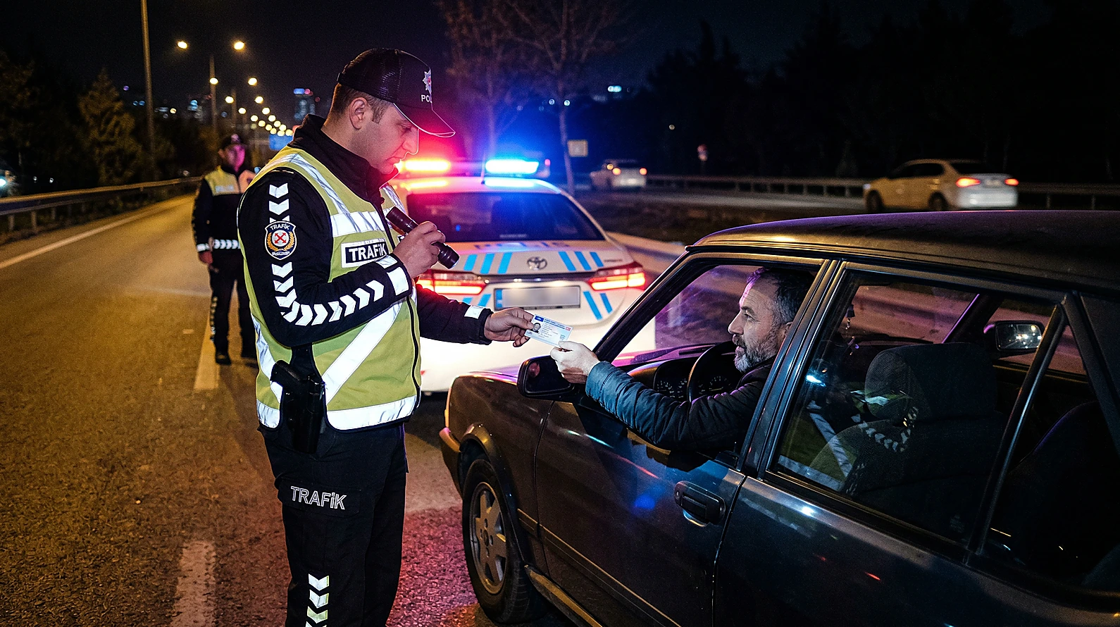 Trafik denetimi sırasında kimlik kontrolü yapan polis memuru.